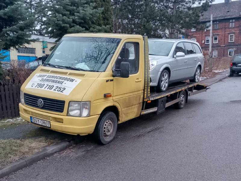 Transport uszkodzonego srebrnego samochodu osobowego na lawecie firmy AutoZłom w Zabrzu